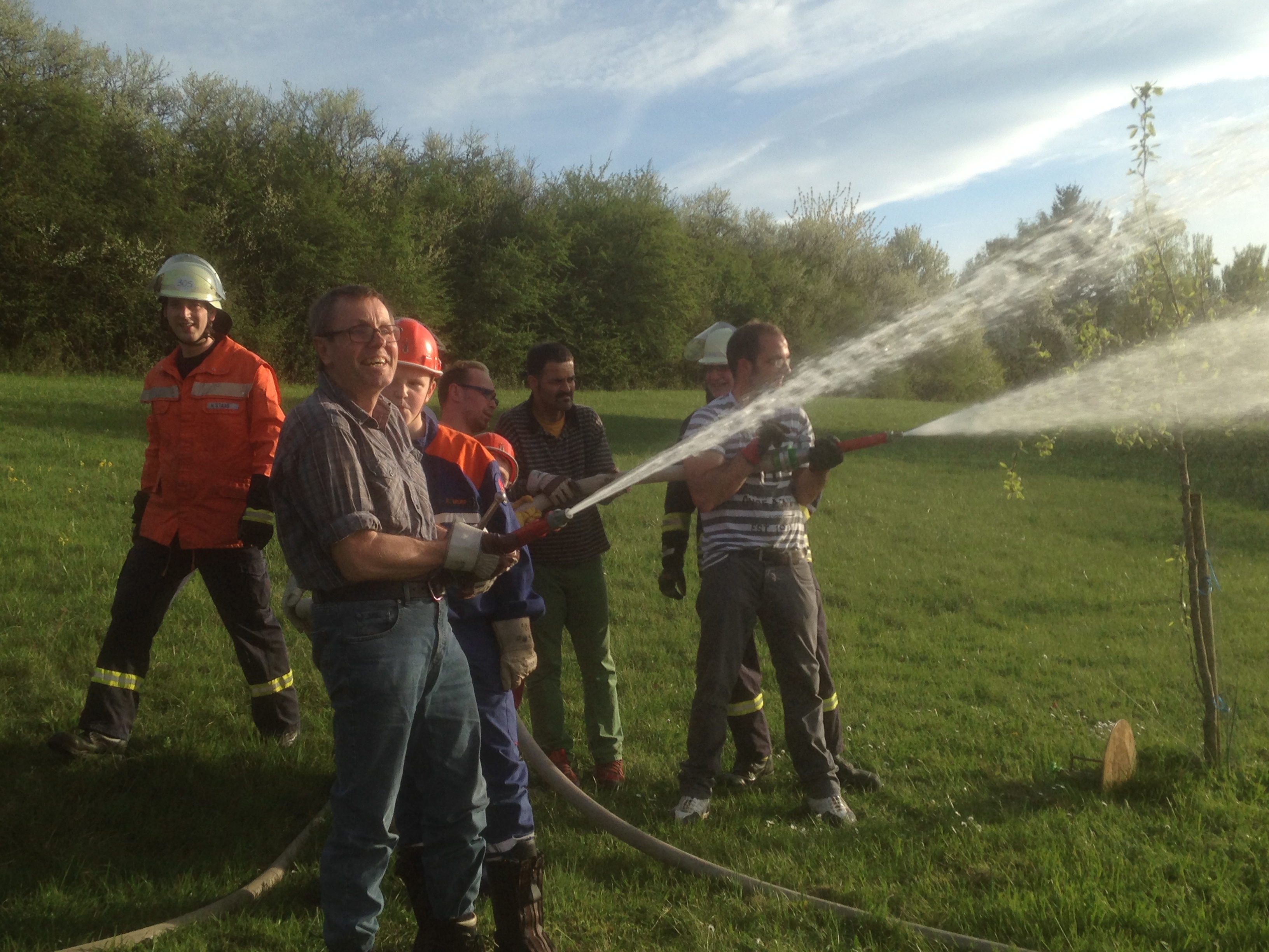 Wasser marsch! Zwei Trupps stehen auf der Wiese jeweils an einem C-Rohr und spritzen Wasser in den Weiher. Es macht ihnen sichtbar sehr viel Freude.