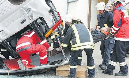 Befreiung einer Person mit der Technik, dies durch die Heckscheibe zu tun. Ein auf dem Dach liegender Kleinwagen, aus dem mit Hilfe von 2 Feuerwehrmännern und 2 Rettungssanitätern eine Person(gespielt) über das Heckfenster
befreit wird